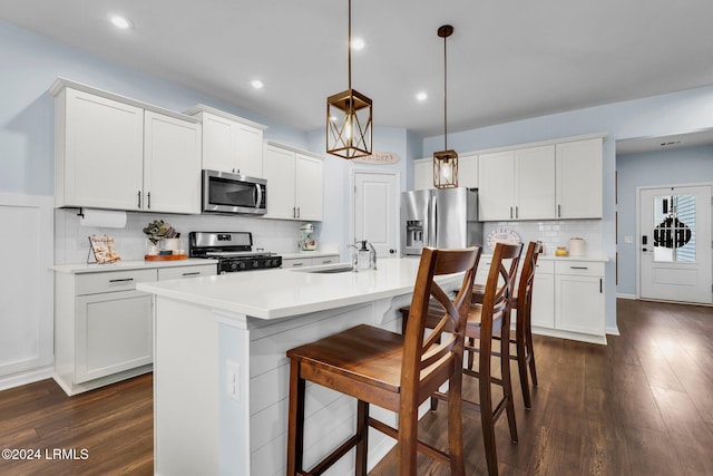 kitchen with pendant lighting, a center island with sink, white cabinets, and appliances with stainless steel finishes