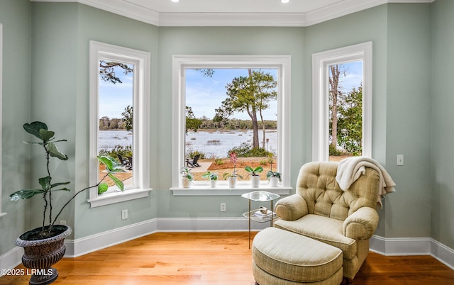 sitting room with a water view, wood finished floors, and a wealth of natural light