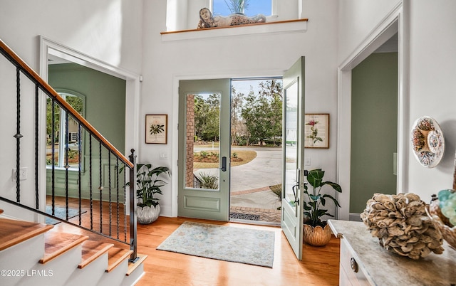 foyer with stairway, a towering ceiling, and light wood-style flooring