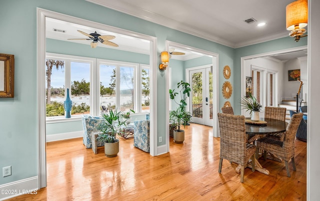 dining space with french doors, crown molding, visible vents, light wood-style flooring, and baseboards