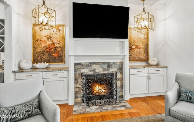 living room with a fireplace, light wood-style flooring, and an inviting chandelier