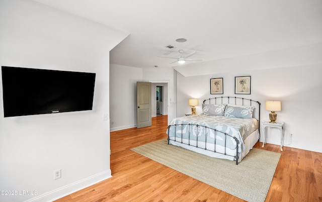 bedroom featuring ceiling fan, visible vents, baseboards, and wood finished floors