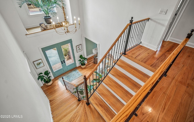 staircase featuring a wealth of natural light, french doors, a towering ceiling, and wood finished floors