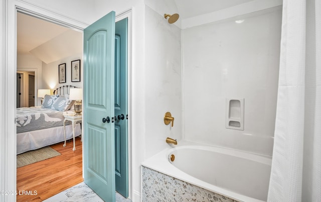 ensuite bathroom featuring wood finished floors, connected bathroom, and shower / bath combo with shower curtain