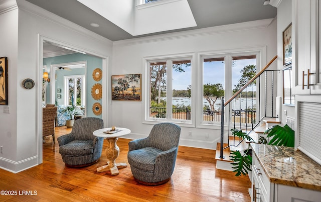 sitting room with light wood-style floors, baseboards, stairs, and ornamental molding