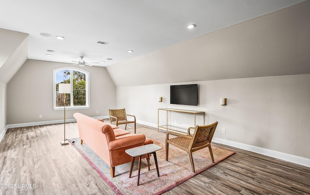 sitting room featuring visible vents, vaulted ceiling, baseboards, and wood finished floors