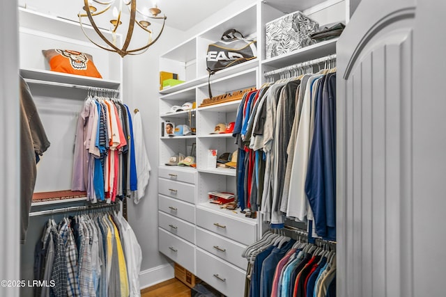 spacious closet with a chandelier and wood finished floors