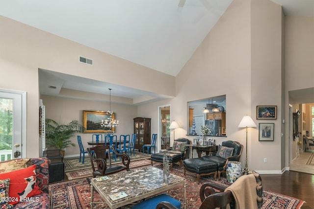 living room featuring a notable chandelier, a tray ceiling, dark hardwood / wood-style floors, and a high ceiling