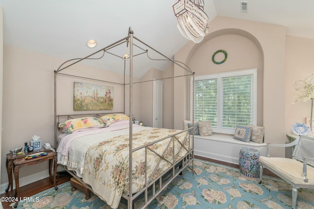 bedroom featuring lofted ceiling, hardwood / wood-style floors, and a notable chandelier