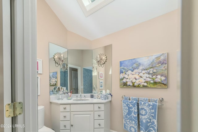 bathroom with vanity, lofted ceiling with skylight, and toilet