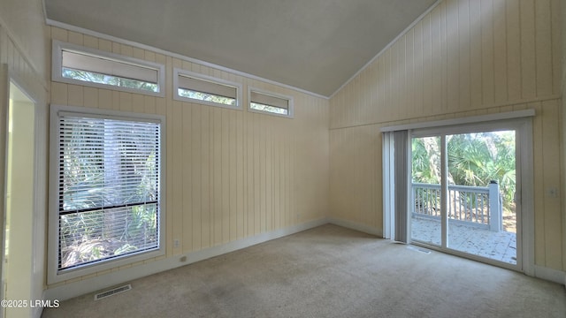 carpeted spare room with visible vents, lofted ceiling, and ornamental molding