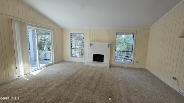 unfurnished living room featuring plenty of natural light, a brick fireplace, carpet, and vaulted ceiling