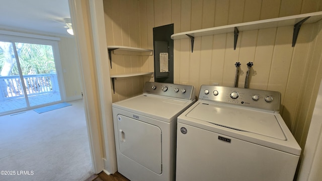 laundry room with washing machine and dryer, dark carpet, wood walls, electric panel, and laundry area