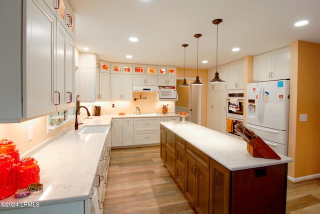 kitchen featuring sink, a center island, hanging light fixtures, white appliances, and white cabinets