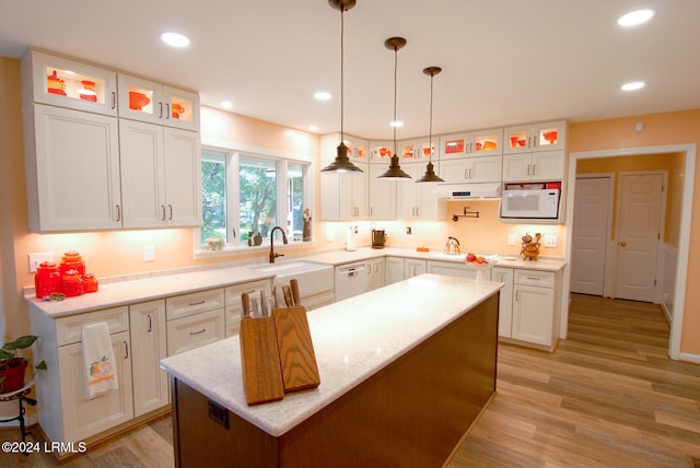 kitchen with white cabinetry, sink, a center island, and white microwave