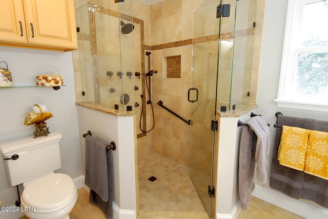 bathroom with tile patterned floors, a shower with door, and toilet