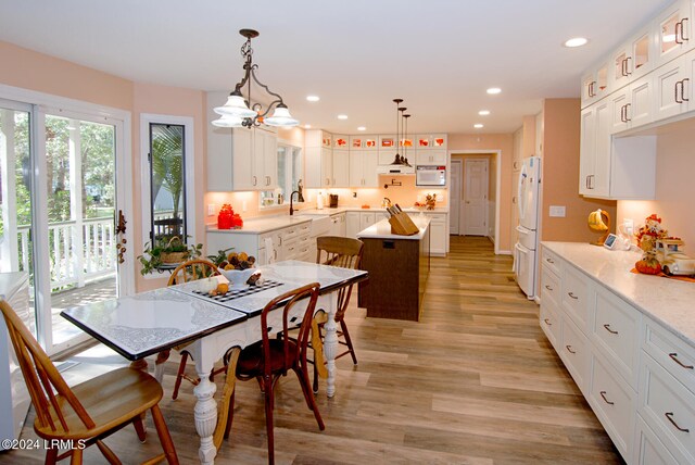 kitchen with white cabinetry, white appliances, and hanging light fixtures