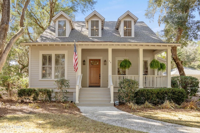 new england style home with covered porch and a shingled roof