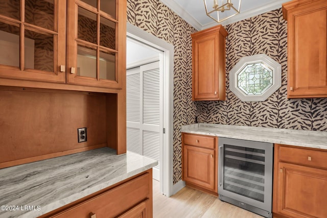 kitchen featuring light stone counters, light hardwood / wood-style flooring, ornamental molding, and beverage cooler