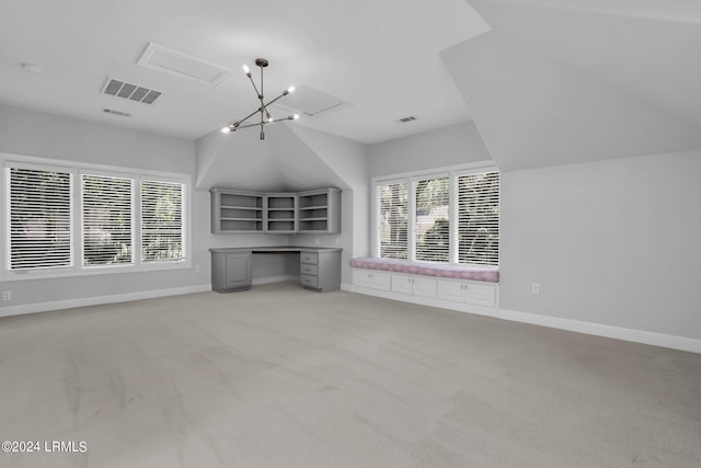 unfurnished living room with lofted ceiling, built in desk, and light colored carpet