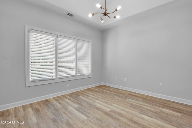 spare room with an inviting chandelier and light wood-type flooring