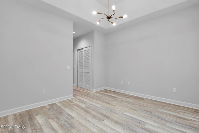 spare room featuring a chandelier and light hardwood / wood-style floors