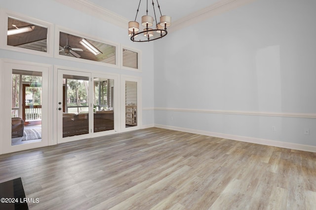 unfurnished living room with crown molding, ceiling fan with notable chandelier, and light hardwood / wood-style floors