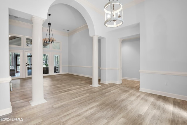 interior space with decorative columns, ornamental molding, light wood-type flooring, and a chandelier