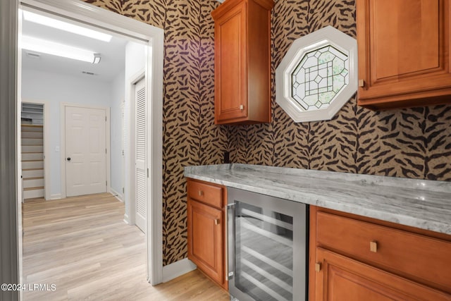 kitchen with wine cooler, light hardwood / wood-style flooring, and light stone countertops