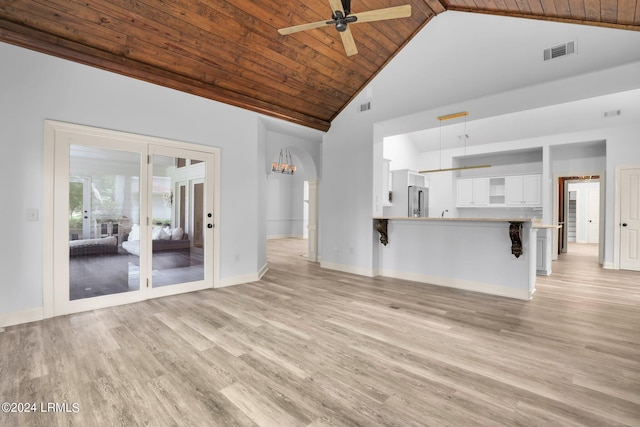 unfurnished living room with high vaulted ceiling, wooden ceiling, ceiling fan, and light hardwood / wood-style floors