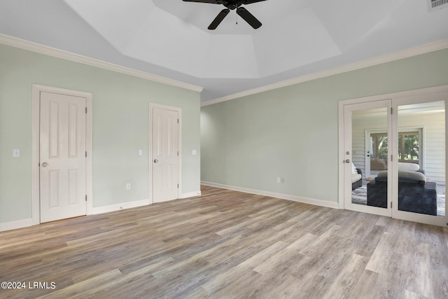 unfurnished room featuring french doors, ornamental molding, a raised ceiling, ceiling fan, and light hardwood / wood-style floors