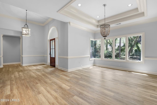 empty room featuring a raised ceiling, crown molding, an inviting chandelier, and light hardwood / wood-style flooring