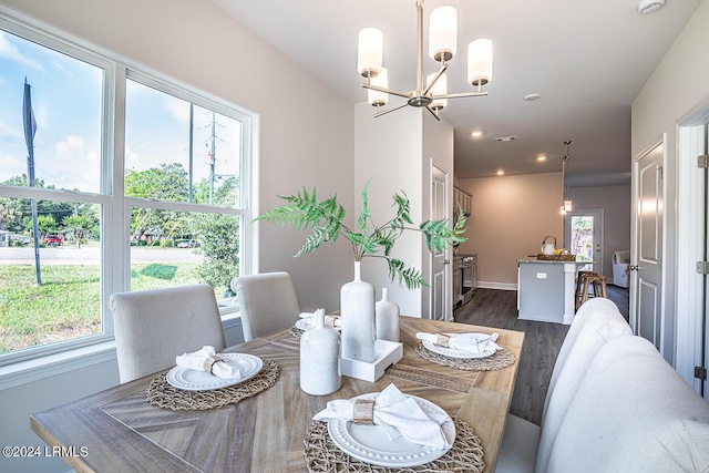 dining area with dark wood-type flooring and a notable chandelier