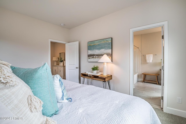 bedroom with ensuite bathroom and light colored carpet