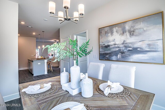 dining area with sink, dark wood-type flooring, and a chandelier