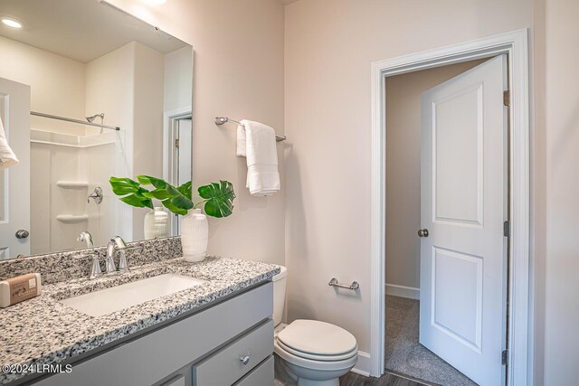 bathroom with vanity, toilet, and a shower