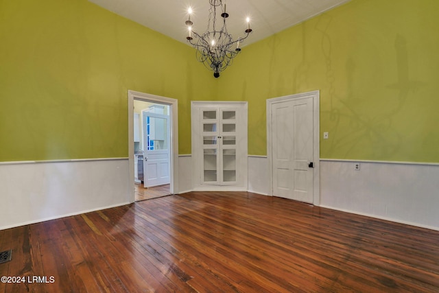 unfurnished room featuring wood-type flooring, a chandelier, and a high ceiling