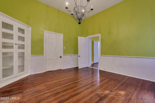 unfurnished room with an inviting chandelier and dark hardwood / wood-style flooring