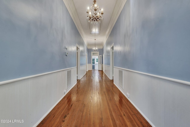 hall with an inviting chandelier, crown molding, and hardwood / wood-style floors