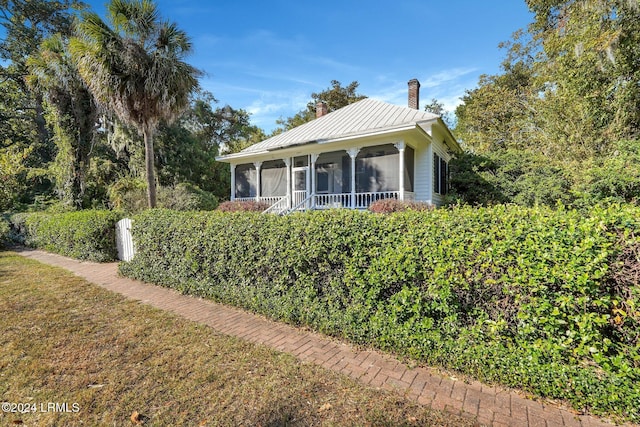 view of home's exterior with a sunroom and a lawn