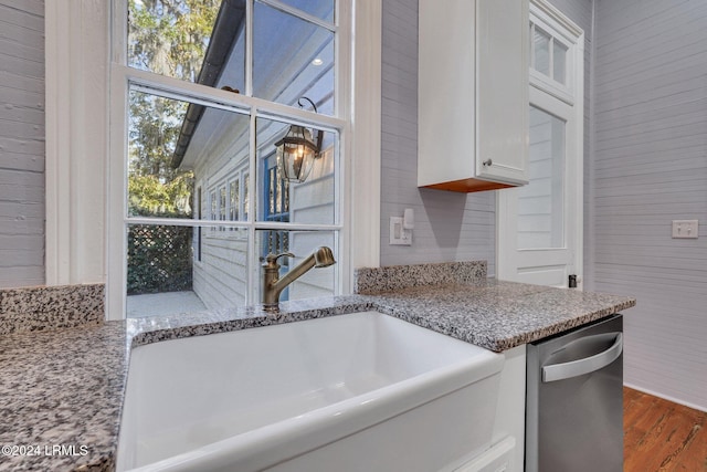 kitchen with dishwasher, sink, white cabinets, light stone countertops, and dark wood-type flooring