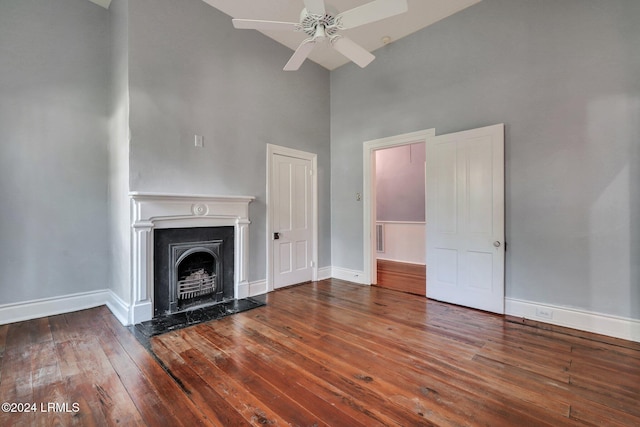 unfurnished living room with hardwood / wood-style flooring, a high ceiling, and ceiling fan