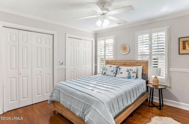 bedroom with baseboards, ornamental molding, multiple closets, and wood finished floors