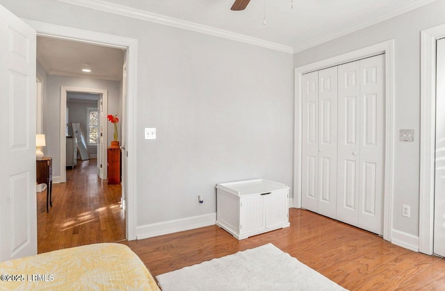 bedroom featuring crown molding, a closet, light wood-style flooring, ceiling fan, and baseboards