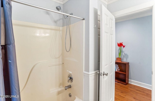 full bathroom featuring shower / bath combination with curtain, crown molding, baseboards, and wood finished floors