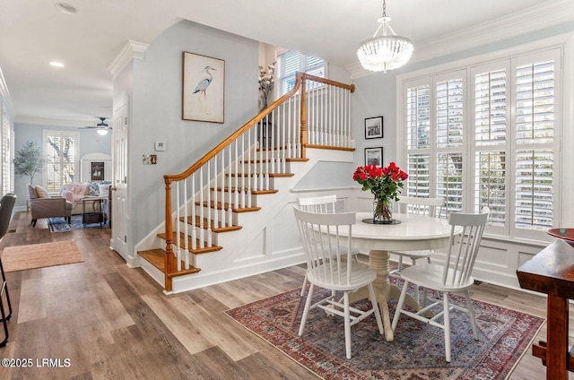 dining room with stairway, a decorative wall, crown molding, and wood finished floors