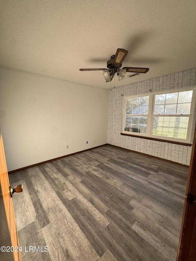 empty room featuring ceiling fan, dark wood-type flooring, and a textured ceiling