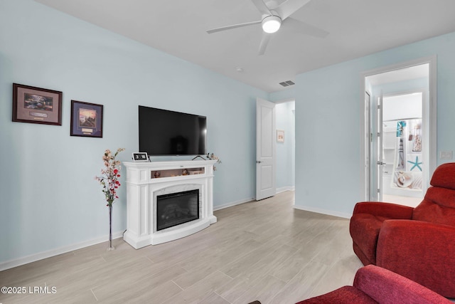 living room featuring light hardwood / wood-style flooring, a high end fireplace, and ceiling fan