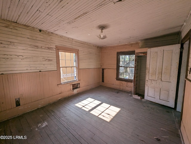 unfurnished room featuring dark wood-type flooring, wooden ceiling, and wooden walls