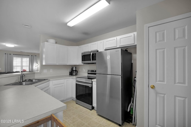 kitchen featuring stainless steel appliances, white cabinetry, and sink